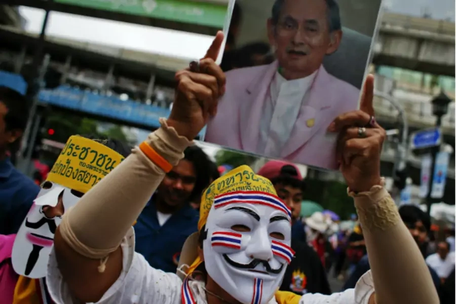 An anti-government protester wearing a Guy Fawkes mask holds a picture of Thai King Bhumibol Adulyadej during a protest in Ban...x-premier Thaksin Shinawatra return from exile without having to serve a jail sentence. (Athit Perawongmetha/Courtesy Reuters)