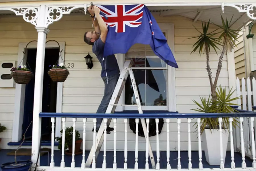 New Zealand resident Brett Plumer nails a national flag to his house in Auckland (Bogdan Cristel/Courtesy Reuters).