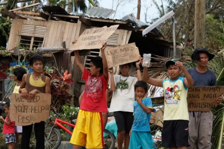 Children hold signs asking for help and food along the highway, after Typhoon Haiyan hit Tabogon town in Cebu Province, central Philippines on November 11, 2013 (Charlie Saceda/Courtesy Reuters).