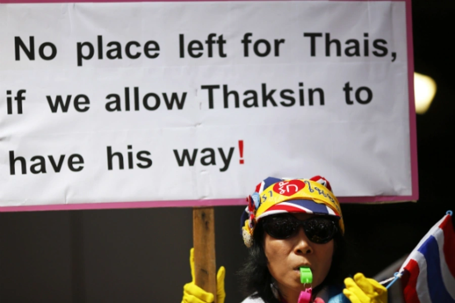 A protester holds a banner as thousands gather against the amnesty bill in Bangkok's central business district on November 6, ... Speaker said on Wednesday, a move that could defuse rising tension on the streets of Bangkok. (Damir Sagolj/Courtesy Reuters)