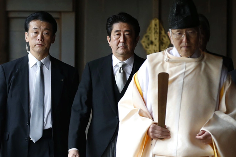 Japan's Prime Minister Shinzo Abe (C) is led by a Shinto priest as he visits Yasukuni shrine in Tokyo December 26, 2013