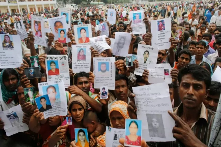 Relatives mourn as they show pictures of garment workers lost in the Rana Plaza building collapse, Savar, Bangladesh, April 28, 2013 (Courtesy Reuters/Andrew Biraj).