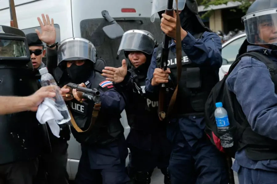 Policemen hold their weapons ready as they pull back during clashes with anti-government protesters near the Government House in Bangkok on February 18, 2014. (Damir Sagolj/Courtesy Reuters)