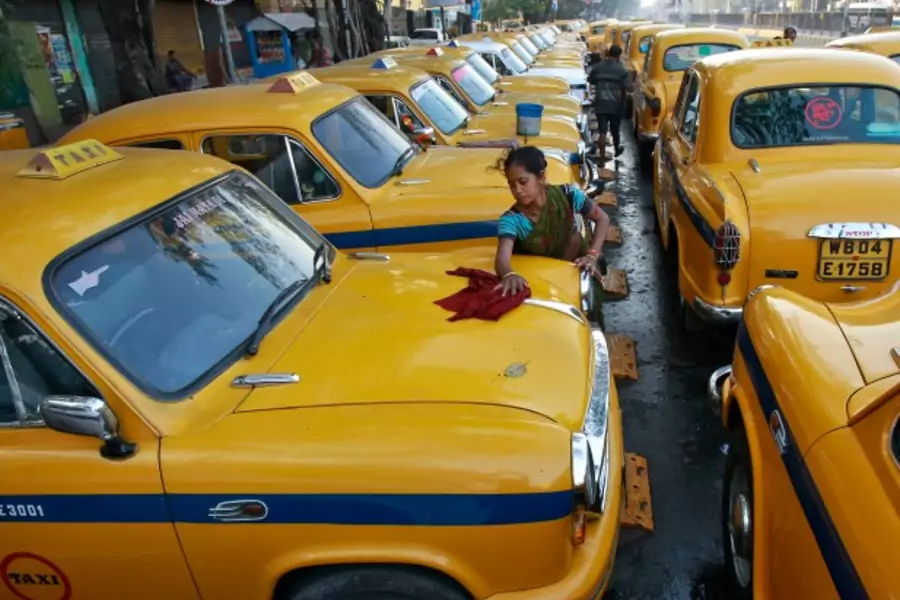 Sumitra Sarkar, 35, cleans a yellow ambassador taxi in Kolkata, India, March 2014 (Courtesy Reuters/Rupak De Chowdhuri).