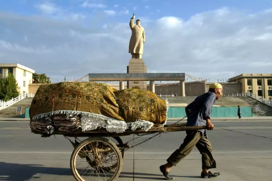 A Uighur worker pulls a cart past a statue of the late chairman Mao Zedong at the People's Square in Kashgar, China, September 2003 (Courtesy Reuters).