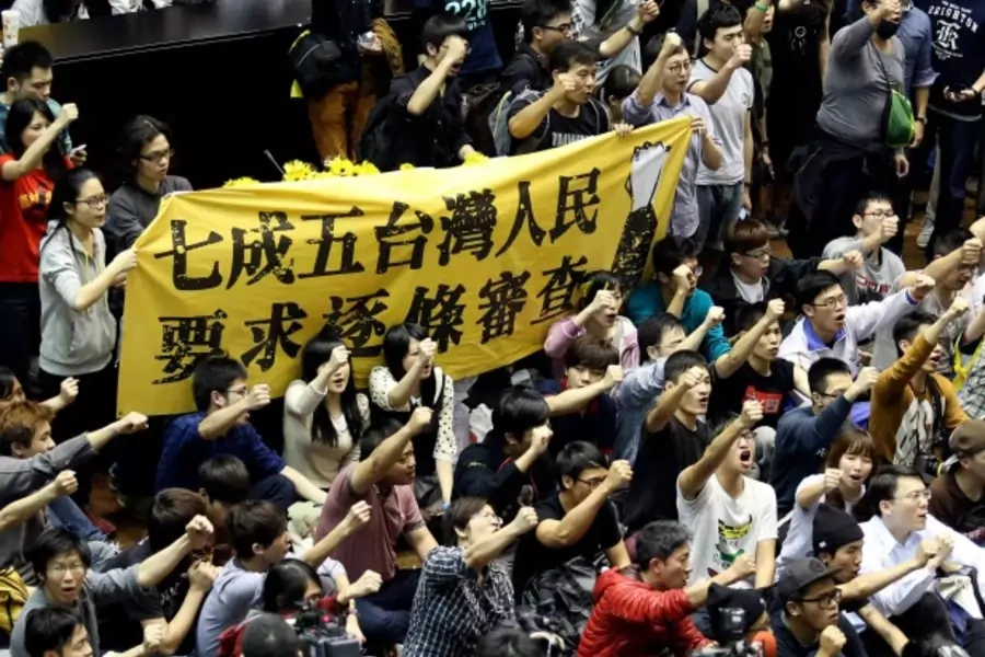 Protestors in Taiwan’s legislature in Taipei hold a banner, “Seventy-five percent of Taiwanese people demand item-by-item review,” on March 19, 2014. (Patrick Lin/courtesy Reuters)