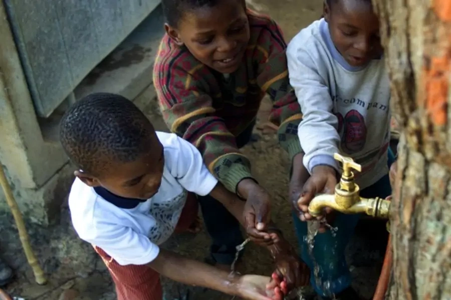 Children play around a communal tap servicing the Imizamo Yethu community near Cape Town, South Africa, August 2002 (Courtesy Reuters/ Mike Hutchings).
