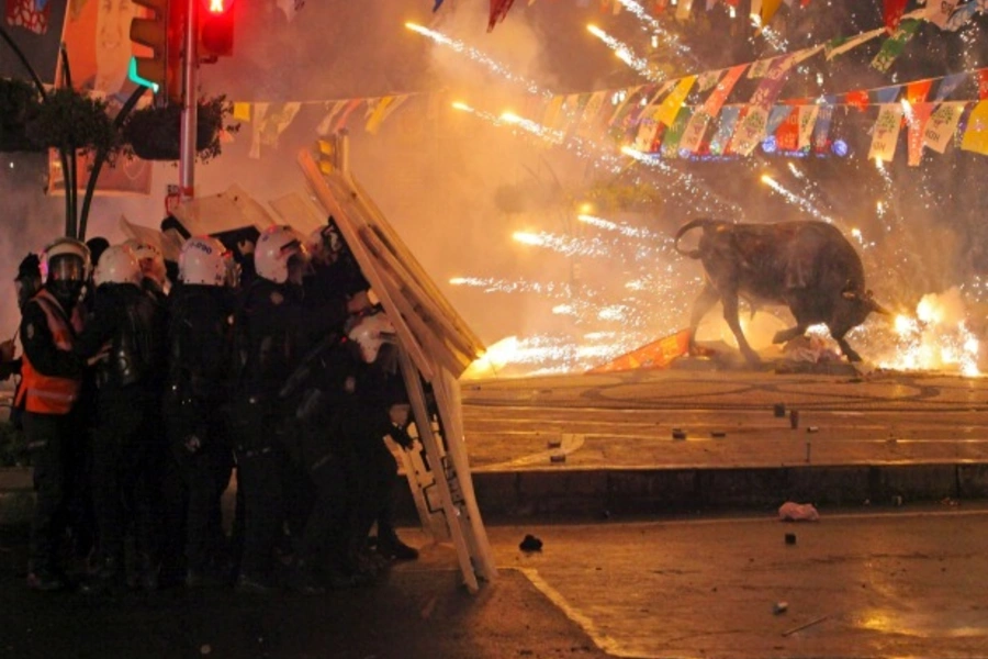 Riot policemen shield themselves as fireworks thrown by protesters explode next to the statue of a bull during an anti-government, anti-corruption protest in Istanbul, Turkey, March 11, 2014 (Courtesy Reuters/Stringer).