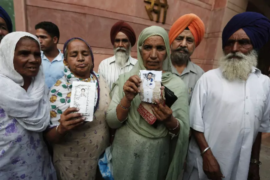 Relatives hold up photographs of Indian workers, who have been kidnapped in Iraq, after their meeting with India's Foreign Minister Sushma Swaraj in New Delhi on June 19, 2014 (Adnan Abidi/Courtesy: Reuters).