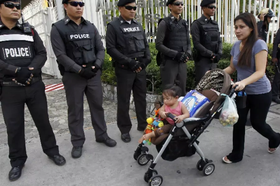 A woman and her child walks past policemen standing guard as anti-coup protesters gather outside the Australian embassy in Bangkok on June 4, 2014 (Chaiwat Subprasom/Courtesy Reuters).