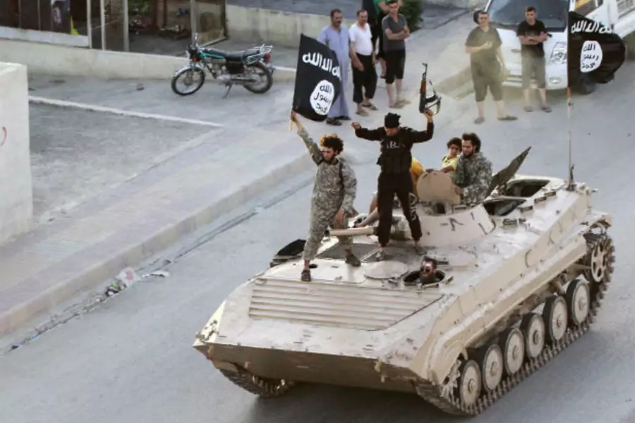ISIS fighters stand atop a tank during a military parade in Syria's Raqqa province on June 30, 2014. The parade was held to celebrate the group's declaration of a "caliphate" spanning its territory in Syria and Iraq one day earlier.