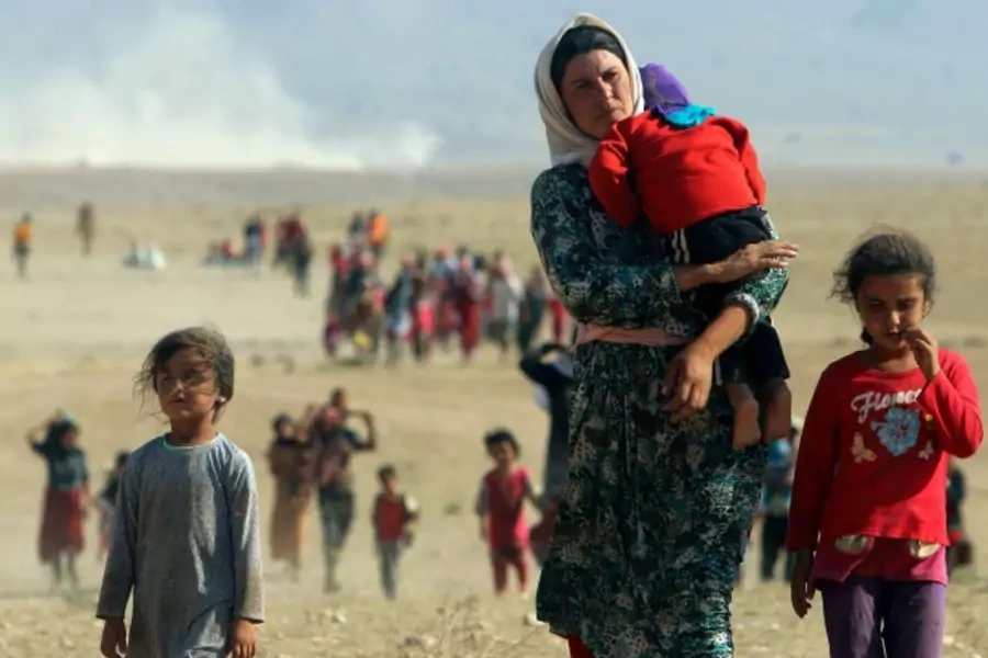 Displaced people from the minority Yazidi sect, fleeing violence from forces loyal to the Islamic State in Iraq and Syria in S...n, walk towards the Syrian border, on the outskirts of Sinjar mountain, in Iraq, August 11, 2014 (Courtesy Reuters/Rodi Said).