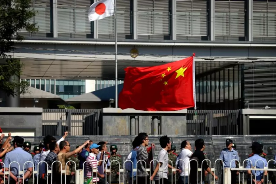 Demonstrators chant slogans and carry a Chinese national flag as they march past riot police outside the main entrance to the ...ry in a long-running row with Japan over a group of disputed islands. REUTERS/David Gray (CHINA - Tags: CIVIL UNREST POLITICS)