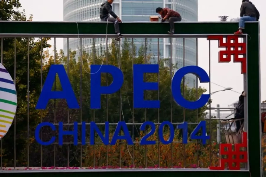 A man (bottom) takes pictures of workers installing lighting on an APEC sign post at the financial district in Beijing, Octobe...ir finance ministers said in a joint statement on Wednesday. REUTERS/Petar Kujundzic (CHINA - Tags: BUSINESS POLITICS SOCIETY)
