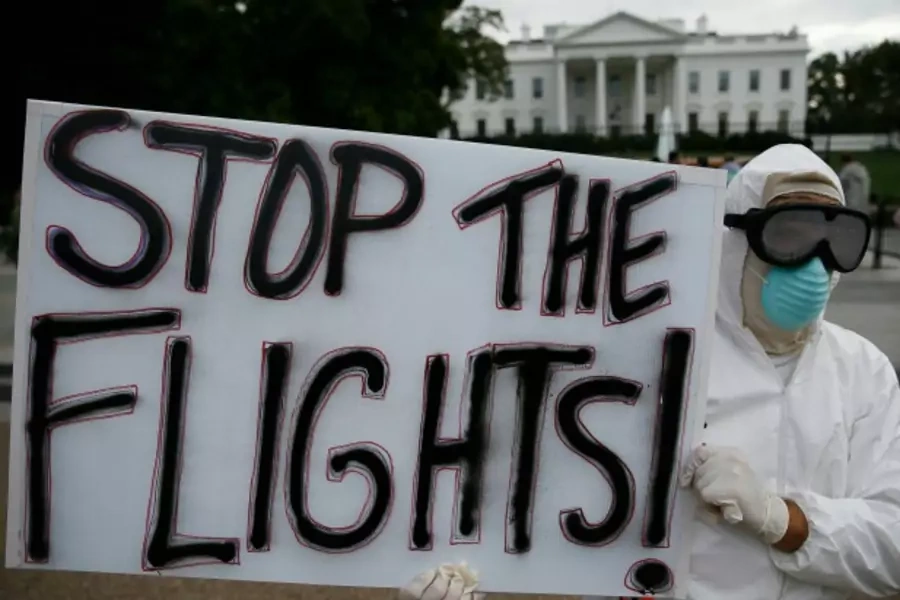 Protestor Jeff Hulbert of Annapolis, Maryland holds a sign reading "Stop the Flights" as he demonstrates in favor of a travel ...e in Washington October 16, 2014. REUTERS/Jim Bourg (UNITED STATES - Tags: POLITICS HEALTH CIVIL UNREST TPX IMAGES OF THE DAY)