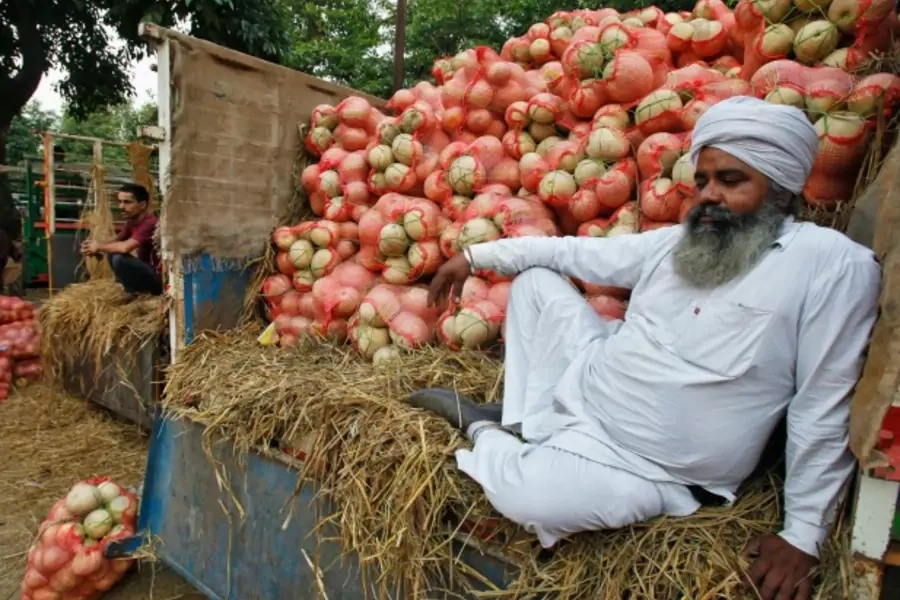 A farmer sits on a trolley loaded with melons as he waits for customers at a fruit and vegetable market in Chandigarh, India, May 2014 (Courtesy Reuters/Ajay Verma).
