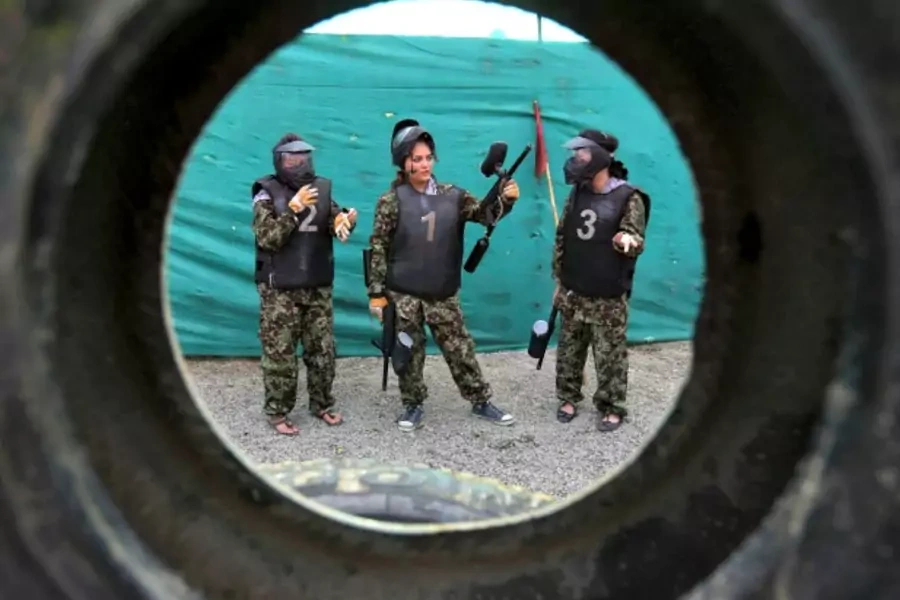 Afghan girls are seen through a tire during their paintball game at Eagle paintball club in Kabul, Afghanistan, September 2014 (Courtesy Reuters/Omar Sobhani).