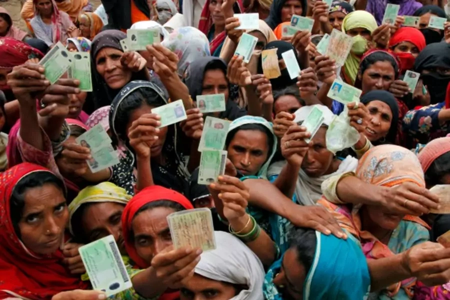 Flood victims show their ID cards to receive food rations at a distribution centre in Muzaffargarh district of Punjab province August 25, 2010 (Courtesy Reuters/Reinhard Krause).