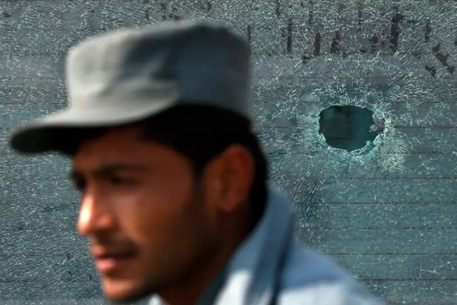 A policeman stands in front of a car window, which has been hit by a bullet, after clashes with protesters in Kabul, Afghanistan, January 31, 2015 (Courtesy Mohammad Ismail/Reuters).