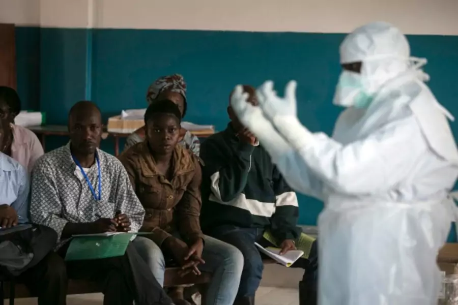 A health worker demonstrates putting on protective gear in a Red Cross facility in the town of Koidu, Kono district in Eastern Sierra Leone, December 2014 (Courtesy Baz Ratner/Reuters).