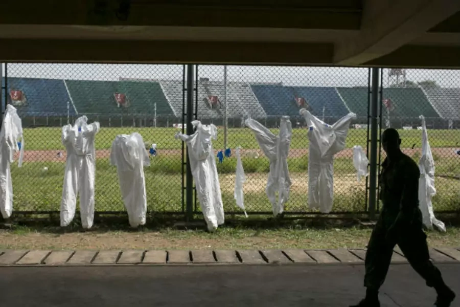 A Sierra Leonean soldier walks past protective clothing drying on a fence in the Ebola Training Academy in Freetown, Sierra Leone, on December 16, 2014.