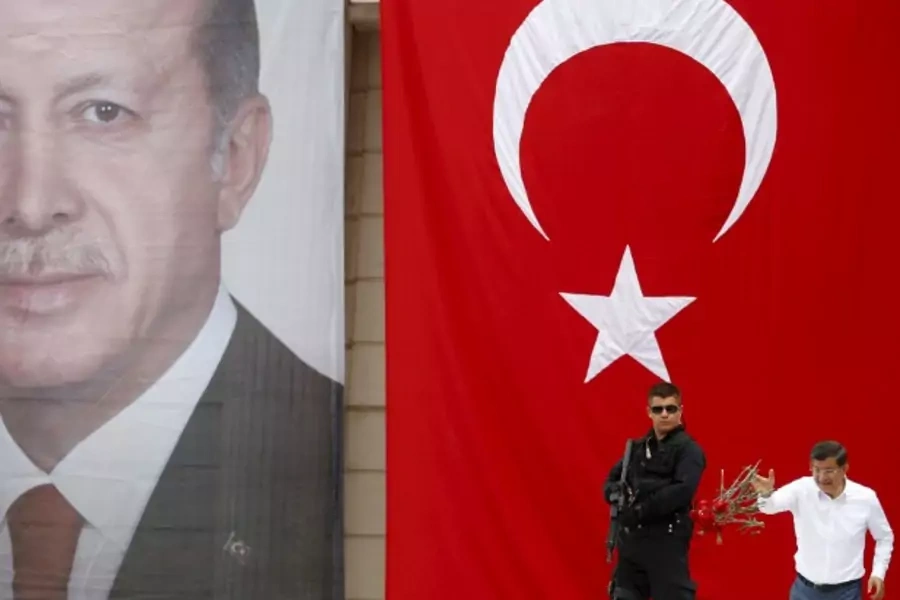 Turkey's Prime Minister Ahmet Davutoglu throws carnations to his supporters as he stands in front of a portrait of President T...g during an election rally for Turkey's June 7 parliamentary election in Istanbul, Turkey, June 3, 2015. (Murad Sezer/Reuters)