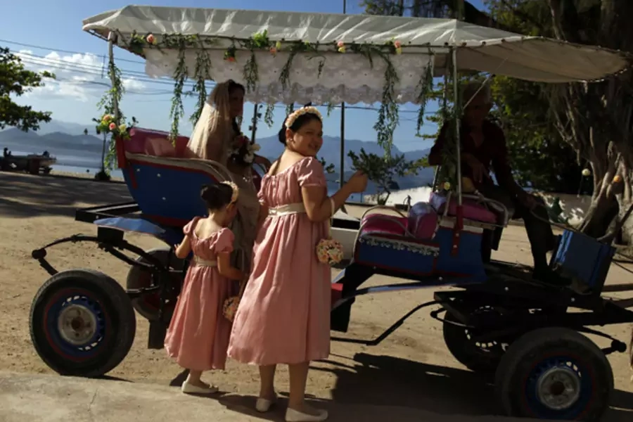 Flower girls wait next to the bride's carriage before a wedding ceremony on Paqueta island in Rio de Janeiro