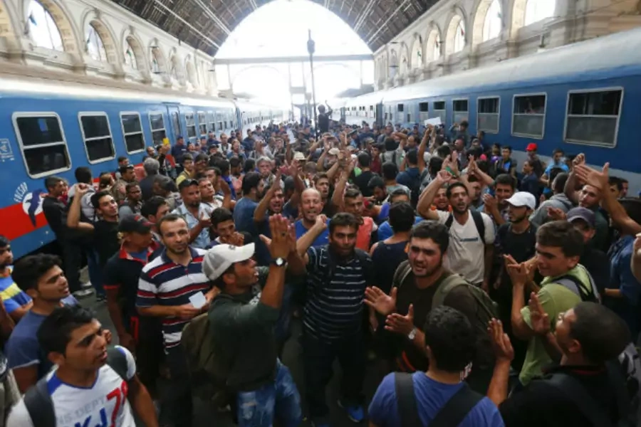 Migrants gesture as they stand in the main Eastern Railway station in Budapest, Hungary, on September 1, 2015.