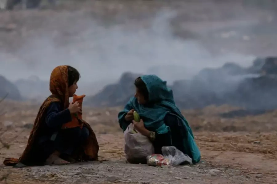 Girls sit near a dumping ground in Peshawar (Reuters/A. Ali).