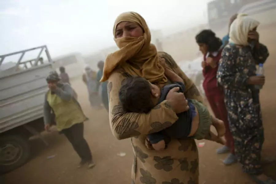 A Kurdish Syrian refugee waits for transport during a sand storm. (REUTERS/Murad Sezer)