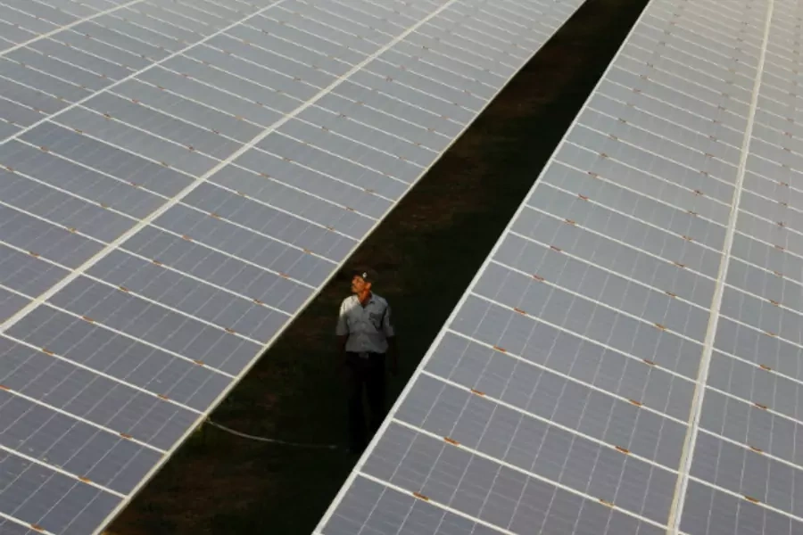 A private security guard walks between rows of photovoltaic solar panels inside a solar power plant at Raisan village in Gujarat (Reuters/Amit Dave)
