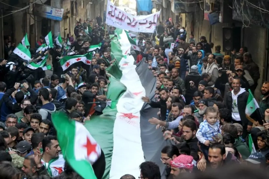 Protesters carry a Free Syrian Army flags during an anti-government protest in the al-Sukari neighborhood of Aleppo, Syria (Abdalrhman Ismail/Reuters).