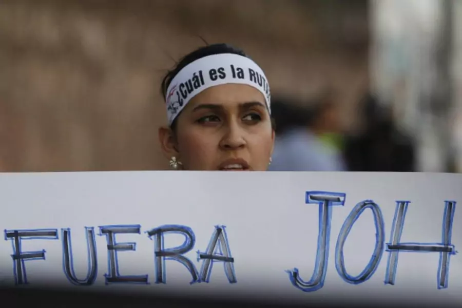 A demonstrator holds a sign that reads "Out JOH", in a reference to Honduras' President Juan Orlando Hernandez, during a march...tion of Hernandez over a $200 million corruption scandal at the Honduran Institute of Social Security (Reuters/Jorge Cabrera).