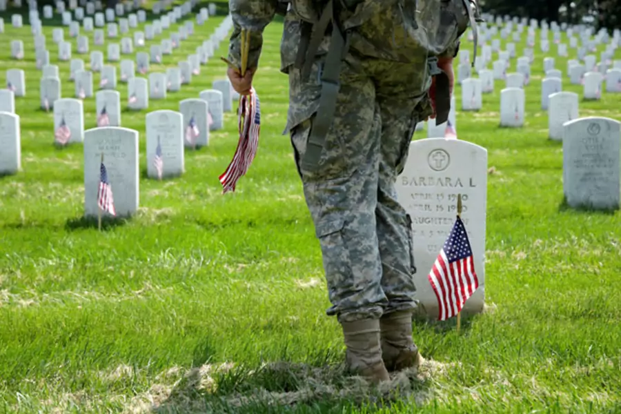 A soldier places flags in front of the graves at Arlington National Cemetery in Washington, DC. (Joshua Roberts/Reuters)