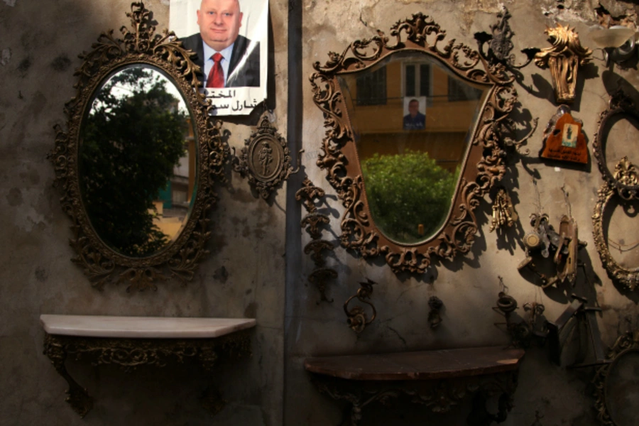 A picture of a candidate for municipality elections is hung near displayed mirrors of an antique shop in Beirut, Lebanon (Alia Haju/Reuters).