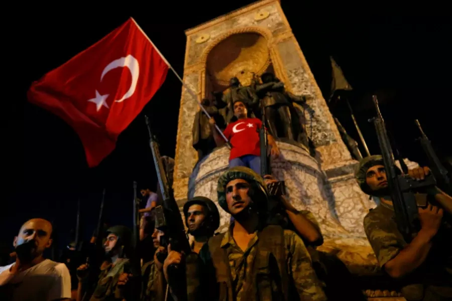 Turkish military stand guard near the the Taksim Square as peiple wave with Turkish flags in Istanbul, Turkey (Murad Sezer/Reuters).