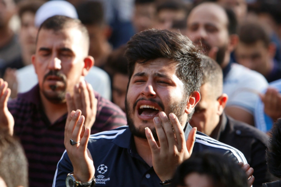 Sunni and Shi'ite Muslims attend prayers during Eid al-Fitr as they mark the end of the fasting month of Ramadan, at the site of a suicide car bomb attack over the weekend at the shopping area of Karrada, in Baghdad, Iraq (Khalid al Mousily/Reuters).