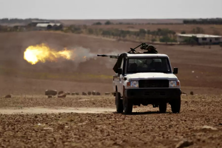 Rebel fighters shoot their weapon towards Dabiq town in northern Aleppo countryside, Syria (Khalil Ashawi/Reuters).