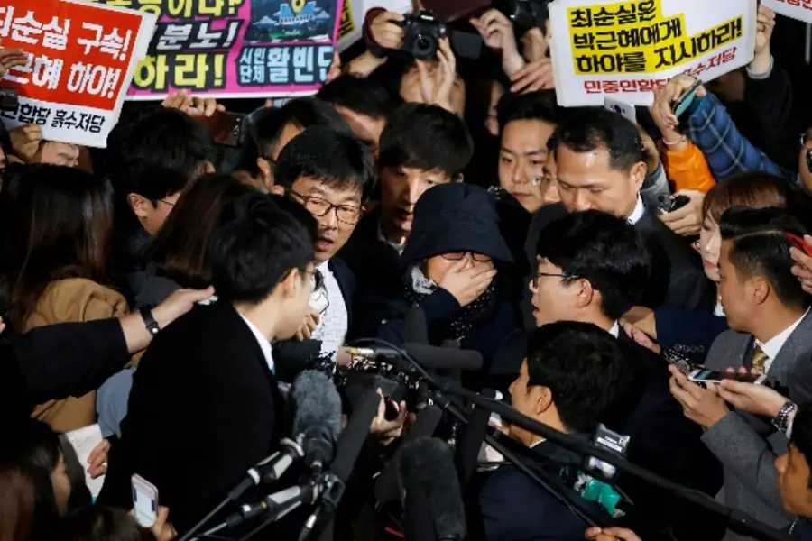 Choi Soon-sil (C), who is involved a political scandal, reacts as she is surrounded by media and protesters upon her arrival a...a, October 31, 2016. The banner (top L) reads "Arrest Choi Soon-sil, Call for Park Geun-hye to step down". REUTERS/Kim Hong-Ji