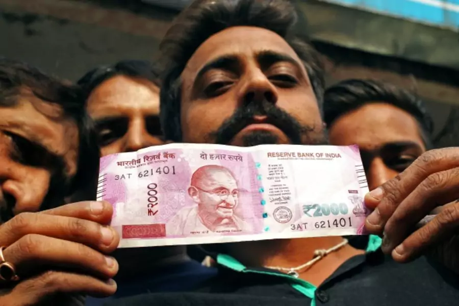 A man displays a new 2000 Indian rupee banknote after withdrawing from a bank (Reuters/Mukesh Gupta).