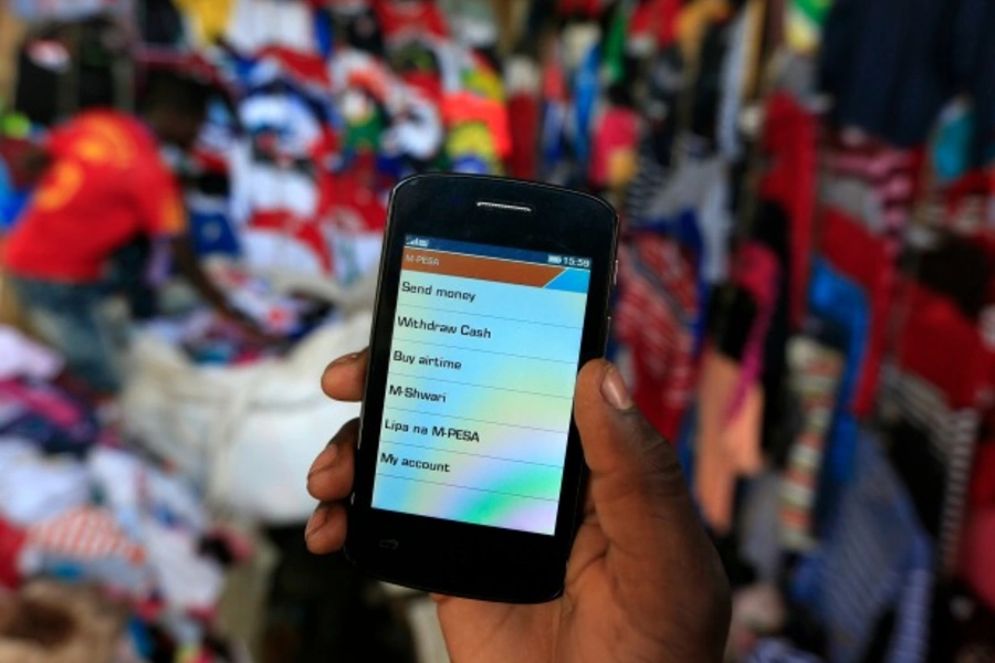 A man holds up his mobile phone showing a M-Pesa mobile money transaction page for the photographer at an open air market in Kibera in Kenya's capital Nairobi (Reuters/Noor Khamis).