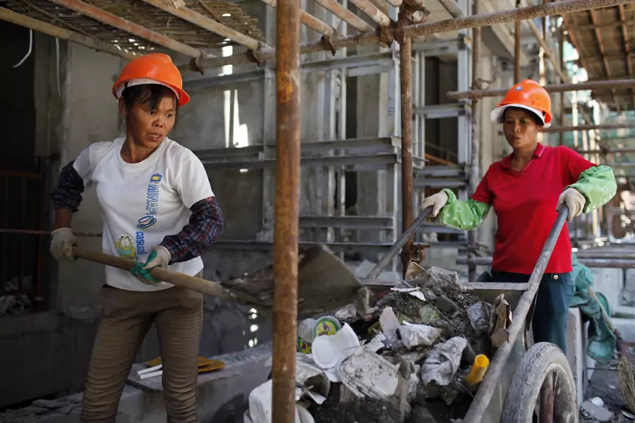Female migrant construction workers collect garbage onto a cart as they work on a shift at a residential construction site in Shanghai August 12, 2013.