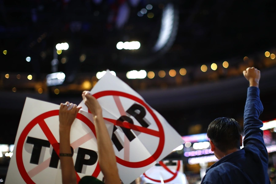 Delegates protesting against the Trans Pacific Partnership (TPP) trade agreement hold up signs. 