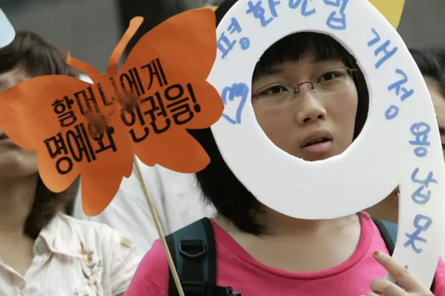A protester holding signs participates in an anti-Japan rally to solve the issue of comfort women, who served the Japanese military during World War Two, in front of the Japanese Embassy in Seoul on July 25, 2007. 