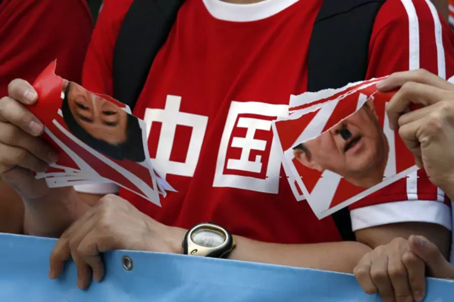 Protesters tear a defaced portrait of Japan's Prime Minister Shinzo Abe during a demonstration outside the Japanese consulate in Hong Kong on September 3, 2014. he characters on the T-shirt read, "China".