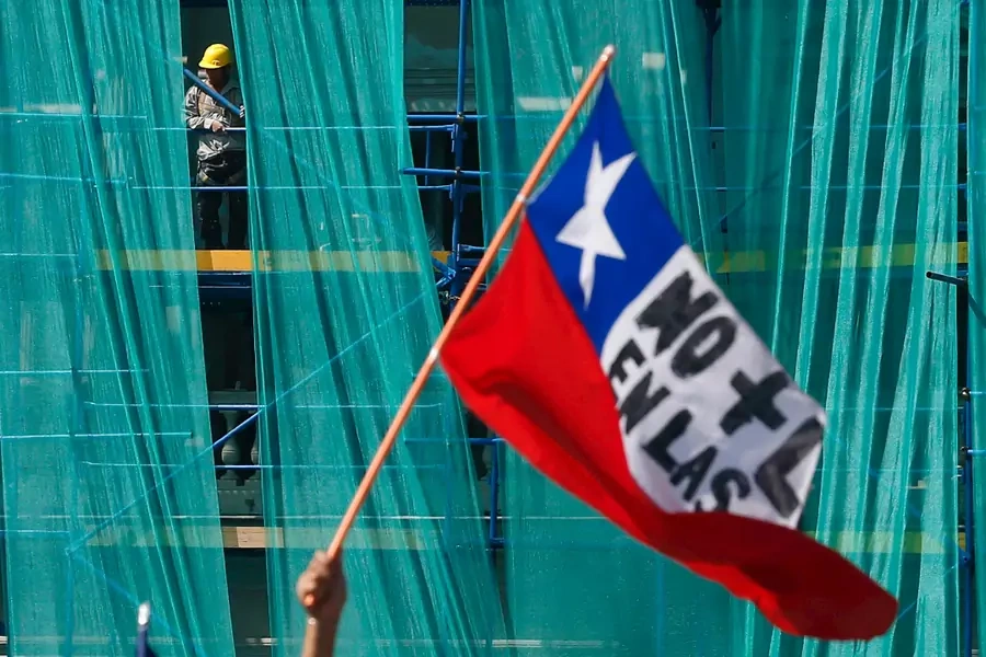 A construction worker looks at workers from the public sector taking part in a rally against a new labour reform law promoted by the government that is pending in Congress in Santiago, Chile, March 22, 2016. 