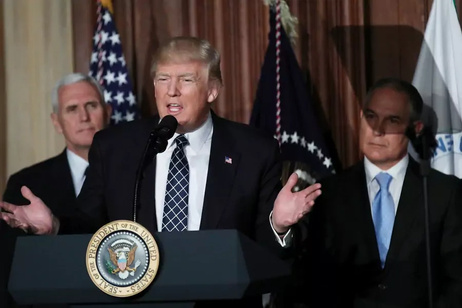 President Donald Trump speaks between Vice President Mike Pence and EPA Administrator Scott Pruitt prior to signing an executive order on "energy independence," eliminating Obama-era climate change regulations, during an event at the EPA