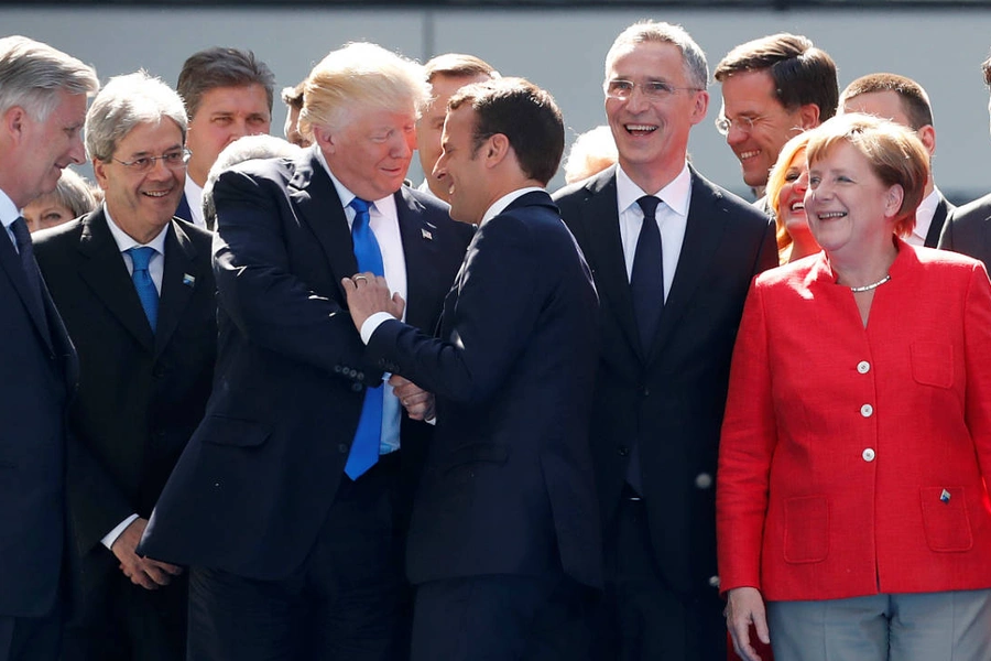 U.S. President Donald Trump shakes hands with French President Emmanuel Macron as NATO member leaders pose for a family picture before the start of their summit in Brussels, Belgium, May 25, 2017.