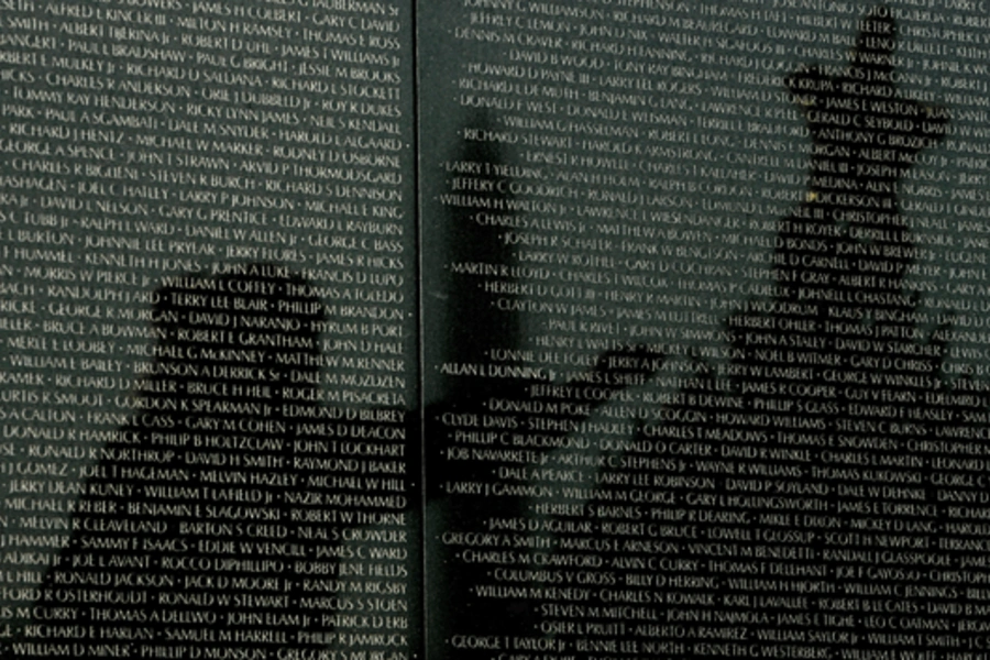 Reflected on the wall listing in the names of American soldiers who died in the Vietnam War, a veteran helps decorate the Christmas tree placed at the Vietnam War Memorial in Washington on December 23, 2008. (Kevin Lamarque/courtesy Reuters)