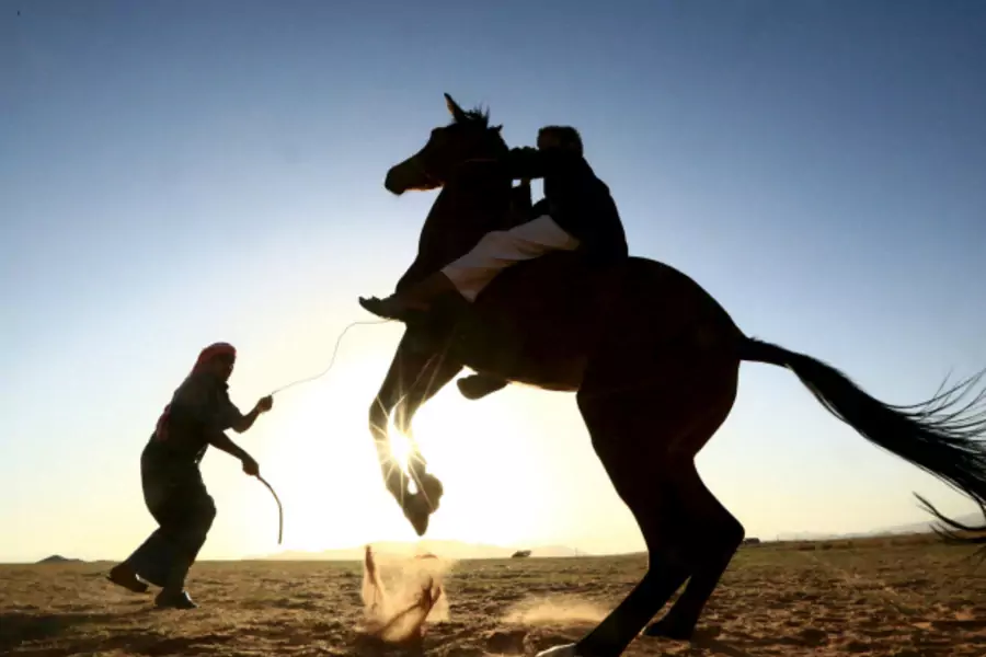 A Saudi man trains his son to ride a horse in a desert near Tabuk, Saudi Arabia (Mohamed Al Hwaity/Reuters).